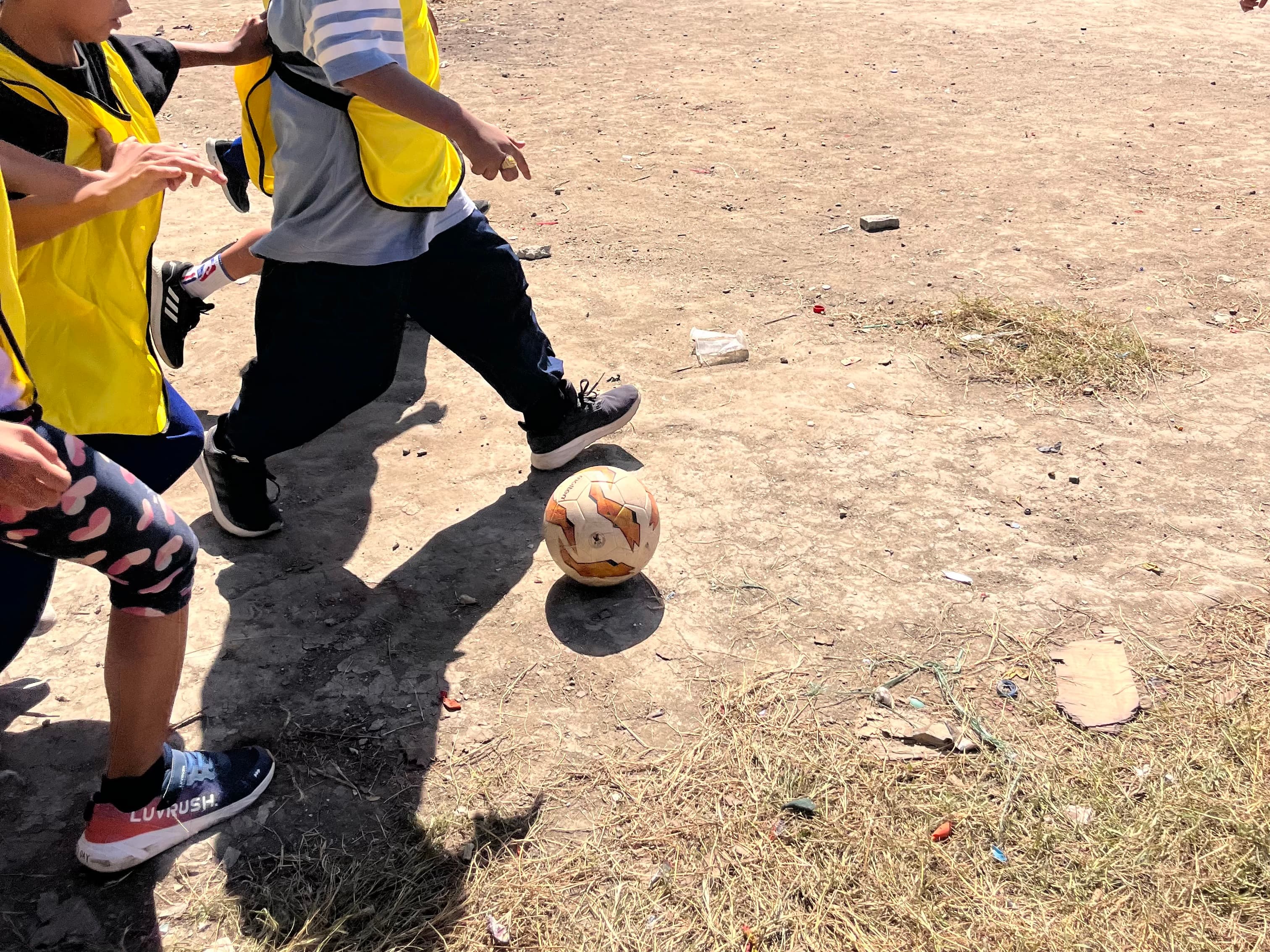 靴を履いてサッカーをする子どもたち